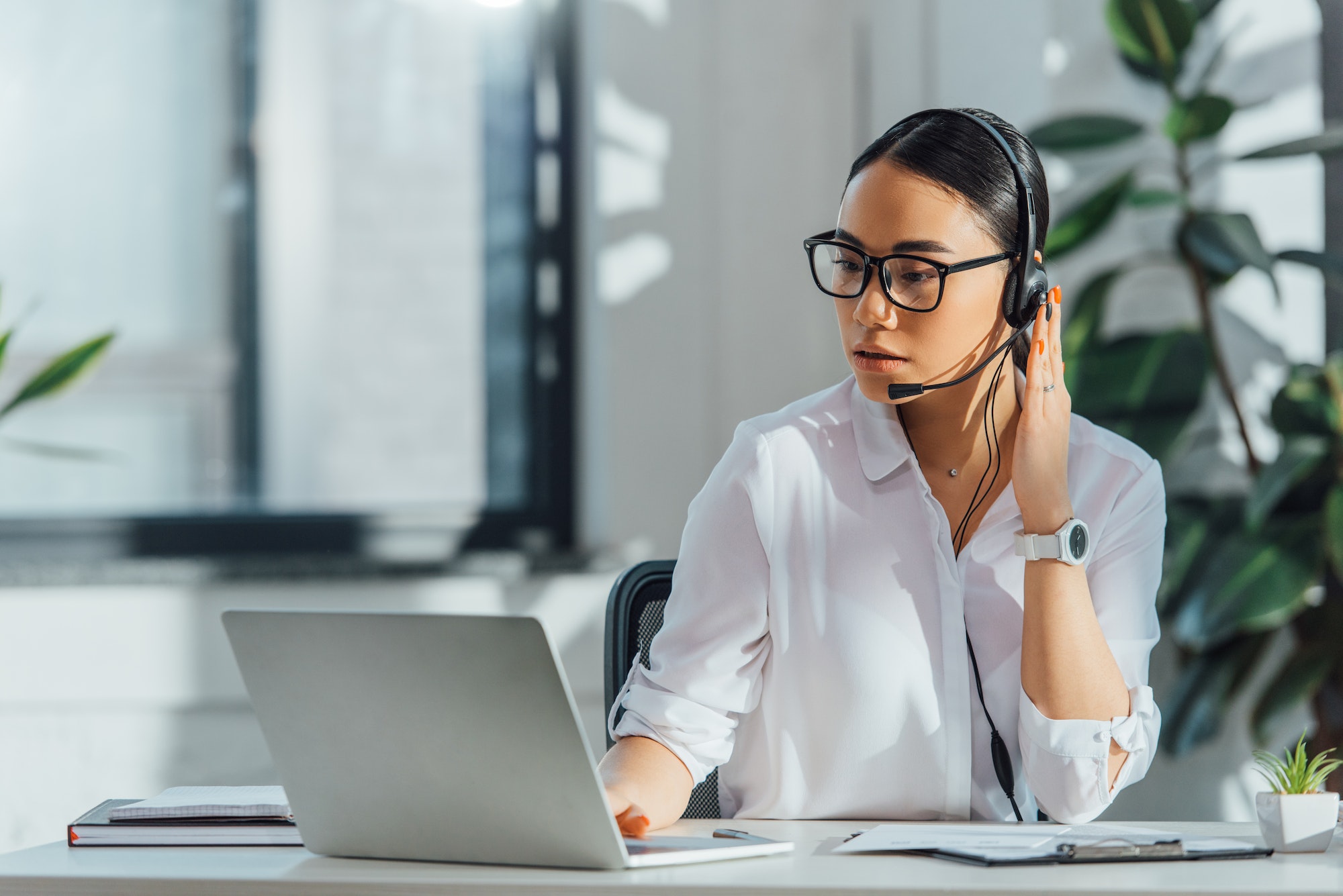 asian translator working online with headset and laptop in office