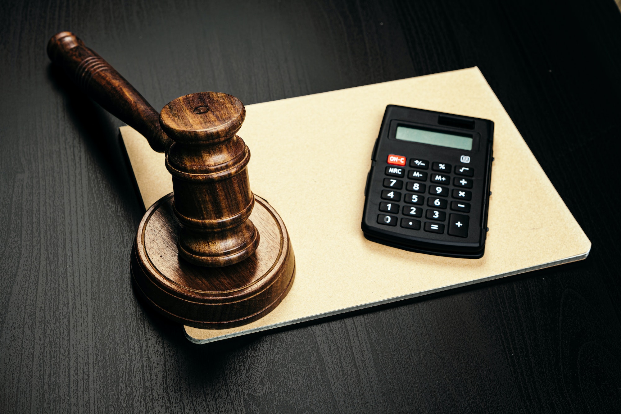 Wooden judge's gavel and calculator on table